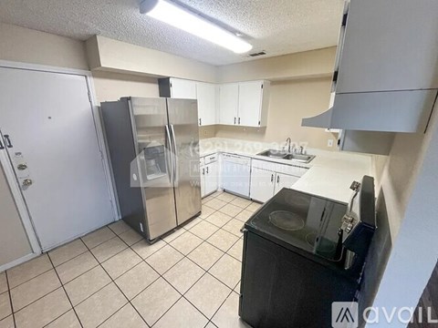 A kitchen with a black fridge and white cabinets.