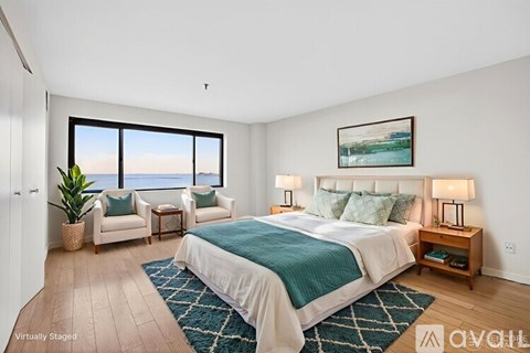 A bedroom with a large bed and a view of the ocean through the window.