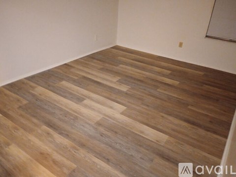 A room with a wooden floor and a window with blinds.
