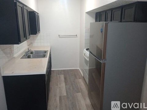 A kitchen with black cabinets and a white fridge.