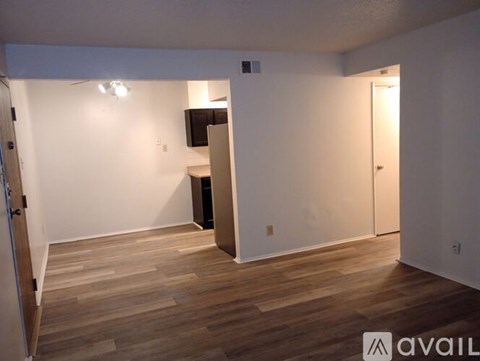 A room with wooden flooring and white walls, with a door on the right side.