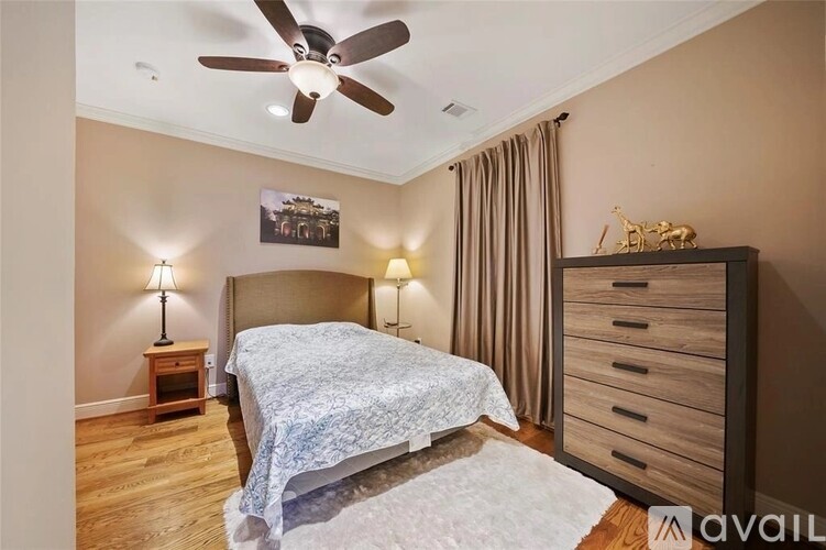 A bedroom with a bed, a dresser, and a ceiling fan.