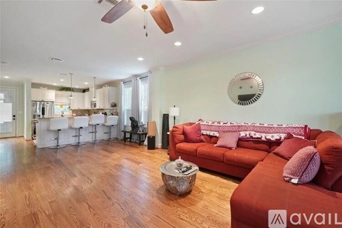 A living room with a red couch and a wooden floor.