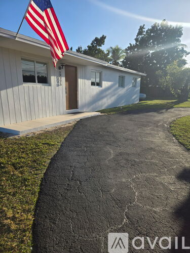 A house with a flag on the front and a driveway leading to the front door.