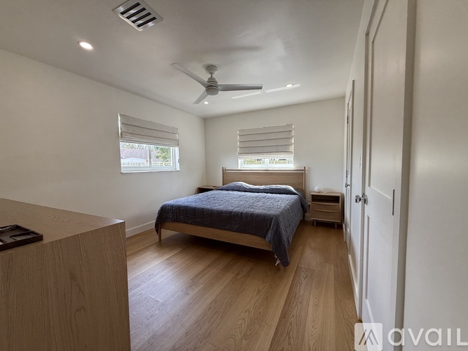 A bedroom with a bed, dresser, and window with blinds.