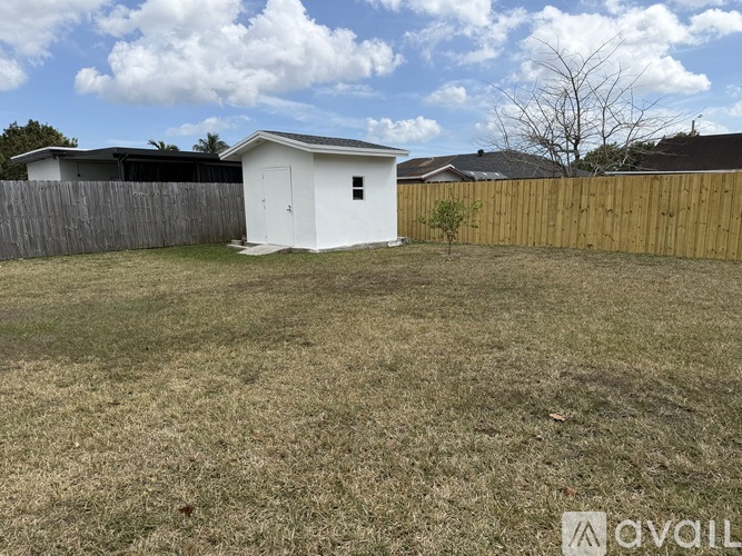 A small white shed sits in a grassy backyard.