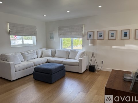 A living room with a white sofa and a blue ottoman.