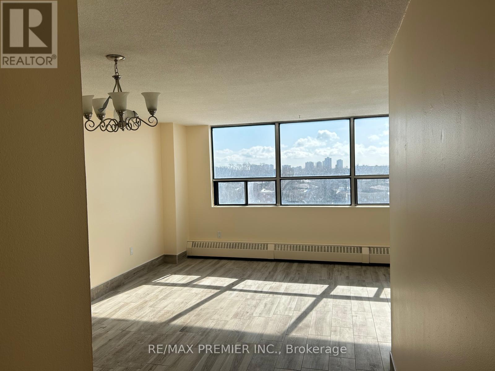 A room with a chandelier and a window overlooking a city skyline.