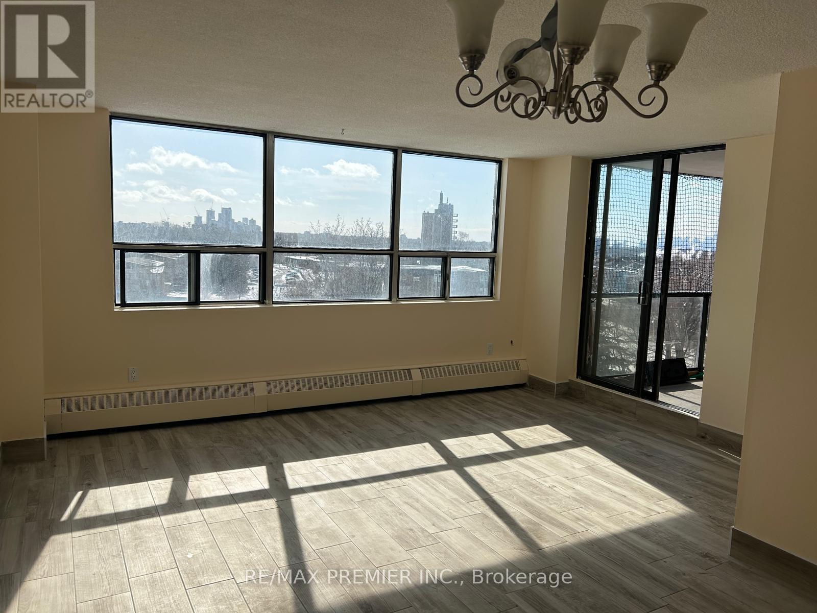 A large, empty room with a view of the city skyline through the windows.