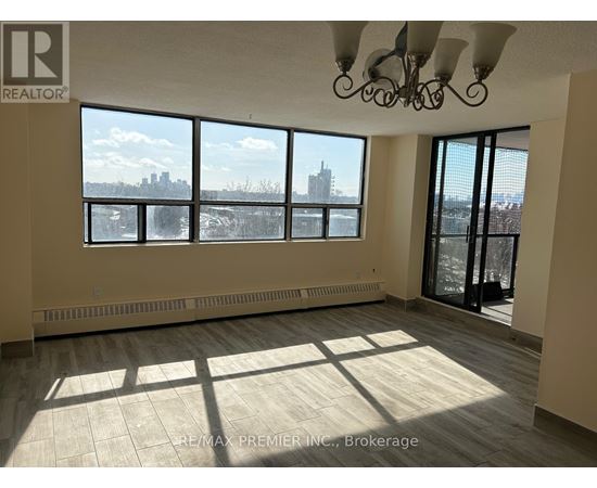A large, empty room with a view of the city skyline through the windows.