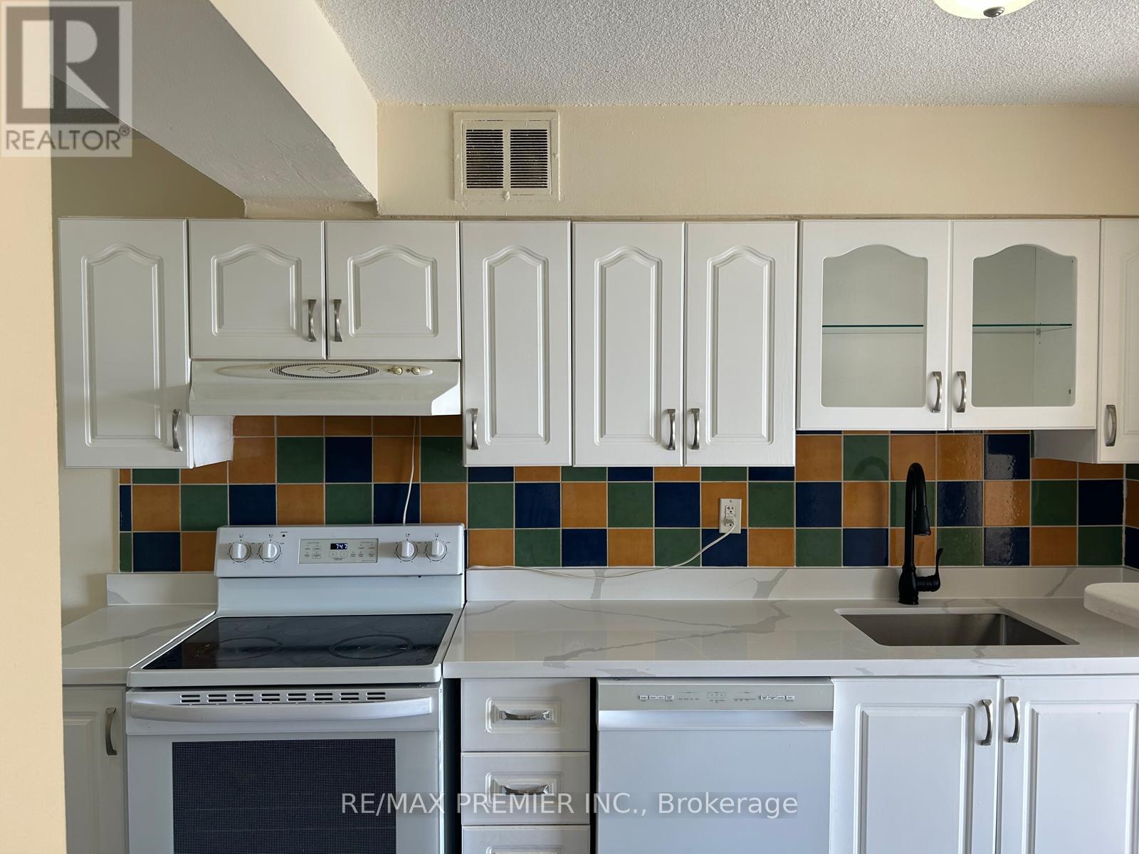 A kitchen with white cabinets and a stove top oven.