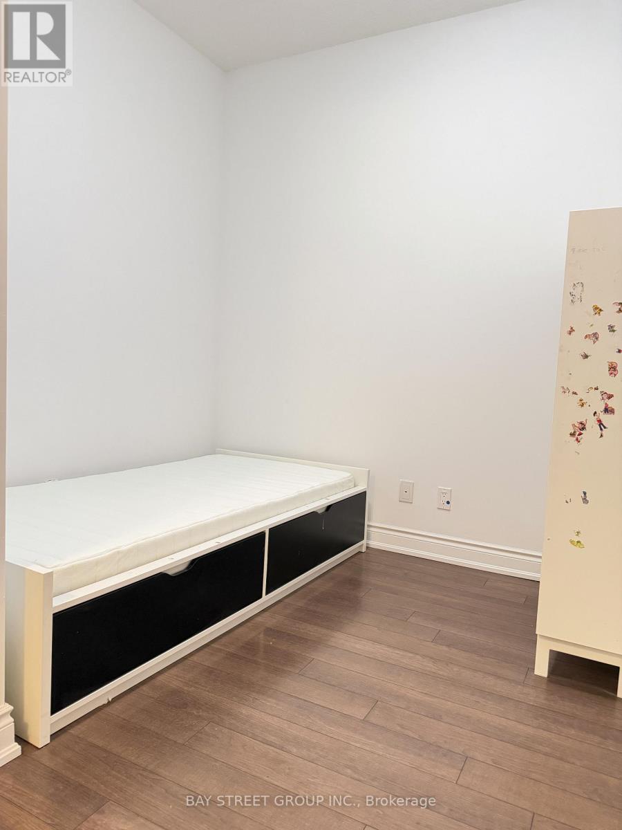 A white bed with black drawers in a room with wooden floors.