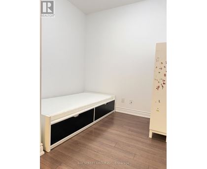 A white bed with black drawers in a room with wooden floors.