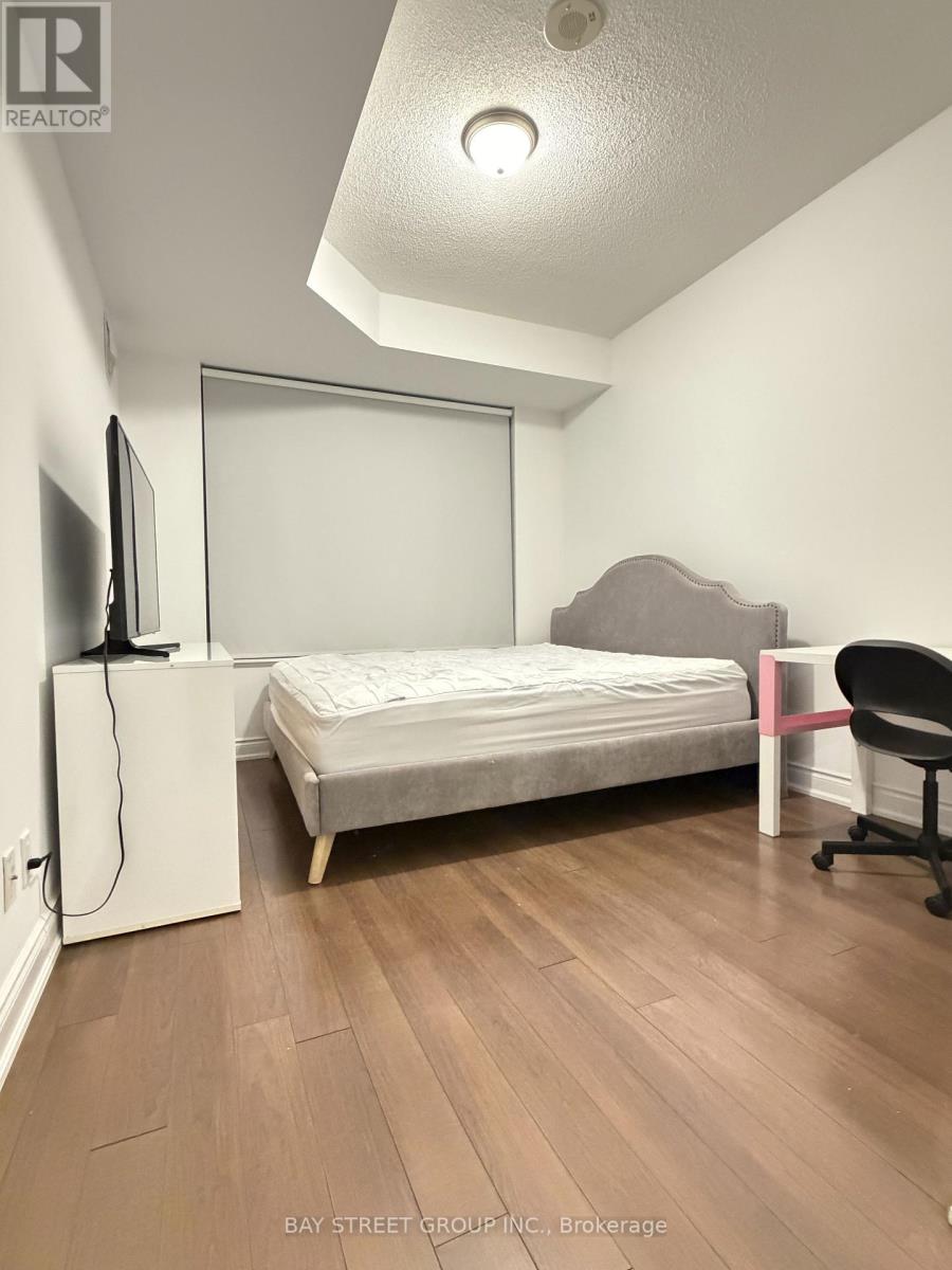 A bedroom with a bed, chair, and television.