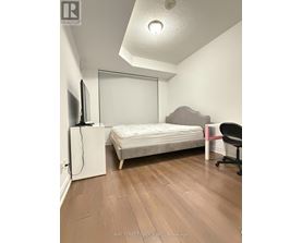 A bedroom with a bed, chair, and television.