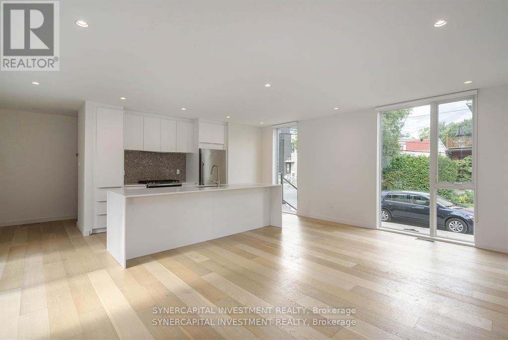 A spacious, well-lit room with wooden flooring and white walls.