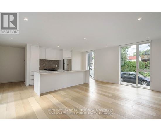 A spacious, well-lit room with wooden flooring and white walls.