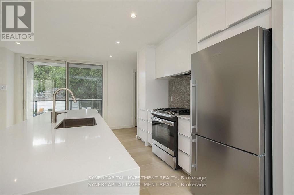 A modern kitchen with a refrigerator, sink, and oven.