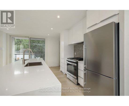 A modern kitchen with a refrigerator, sink, and oven.