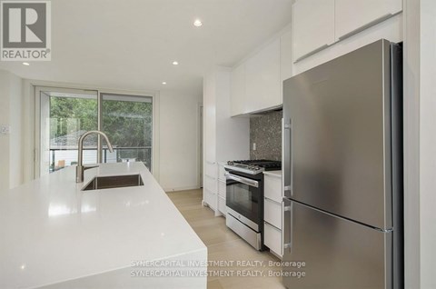 A modern kitchen with a refrigerator, sink, and oven.