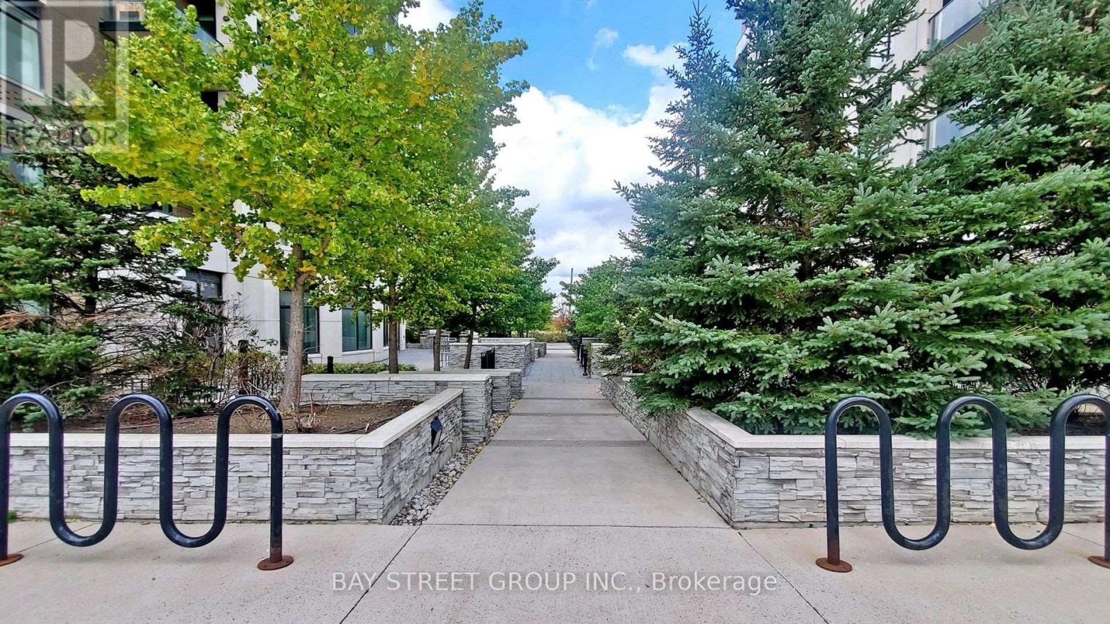 A tree-lined walkway with a metal railing on either side.