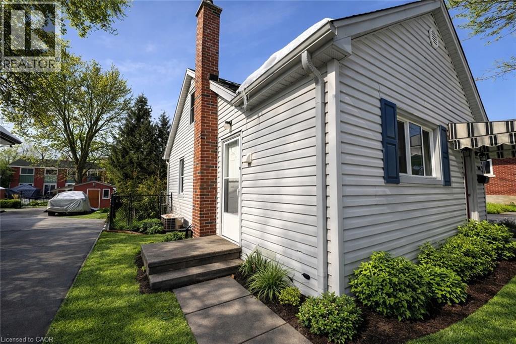 A house with a white siding and a brick chimney is shown.
