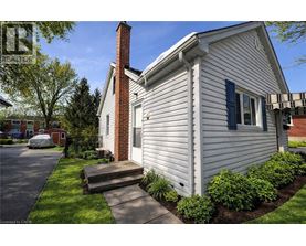 A house with a white siding and a brick chimney is shown.