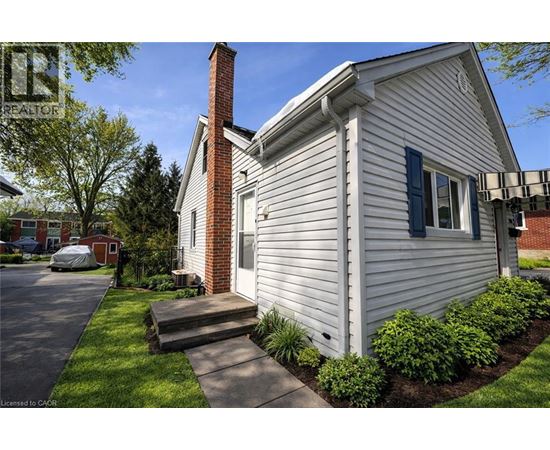 A house with a white siding and a brick chimney is shown.
