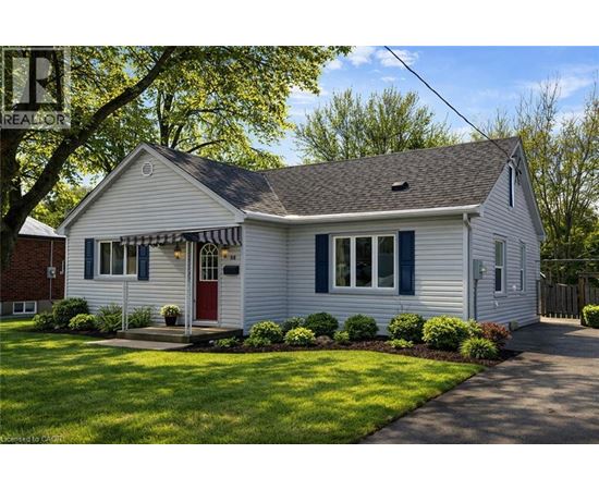 A white house with a red door and a striped awning.