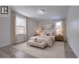 A bedroom with a large bed and a window with curtains.