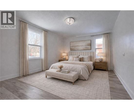 A bedroom with a large bed and a window with curtains.