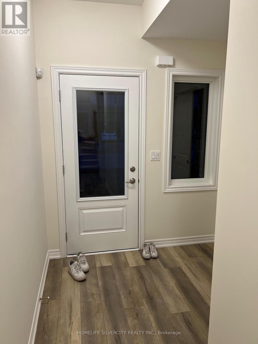 A pair of shoes are on a wooden floor in a room with a white door and a window.