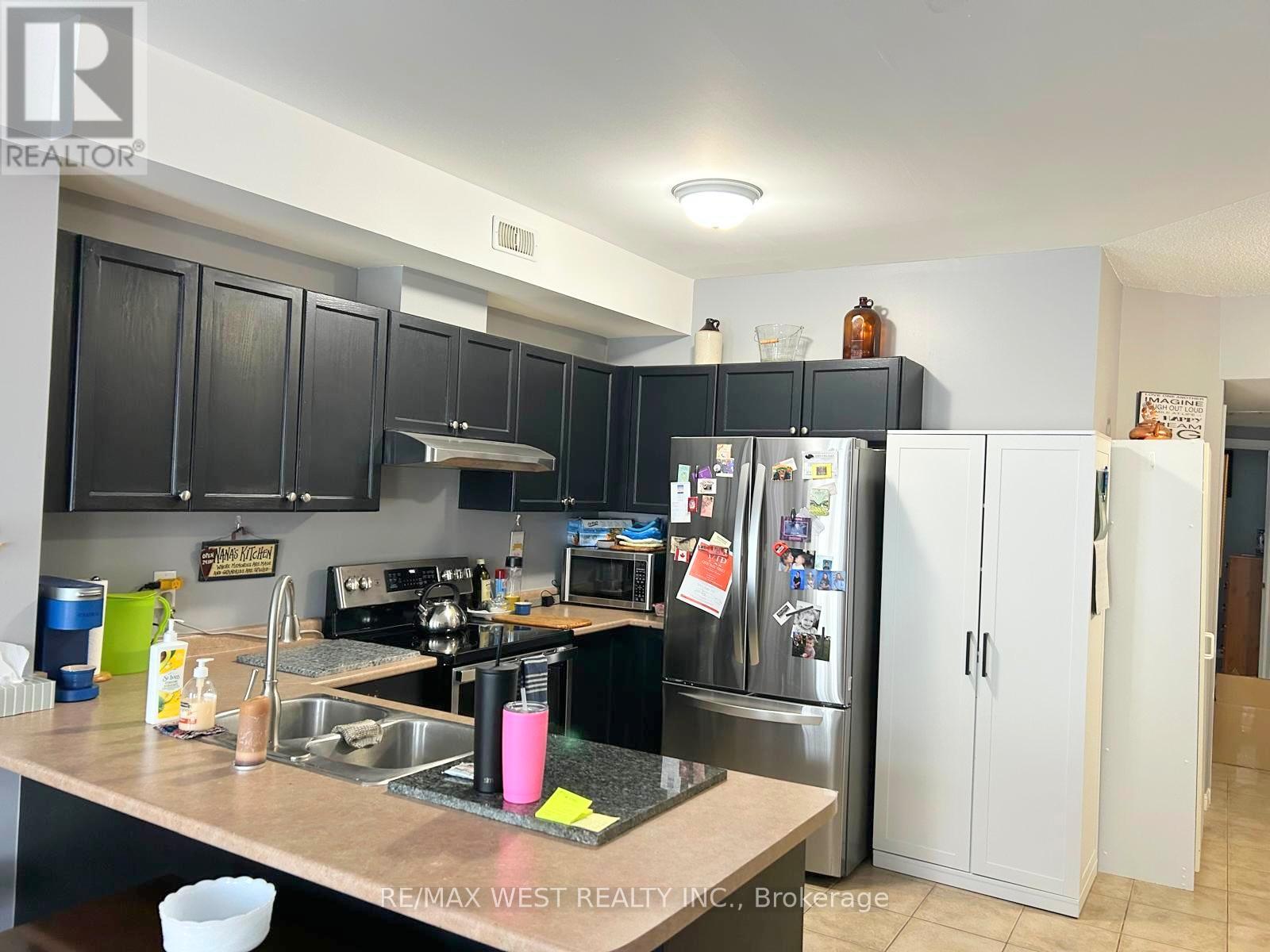 A kitchen with black cabinets and a stainless steel refrigerator.