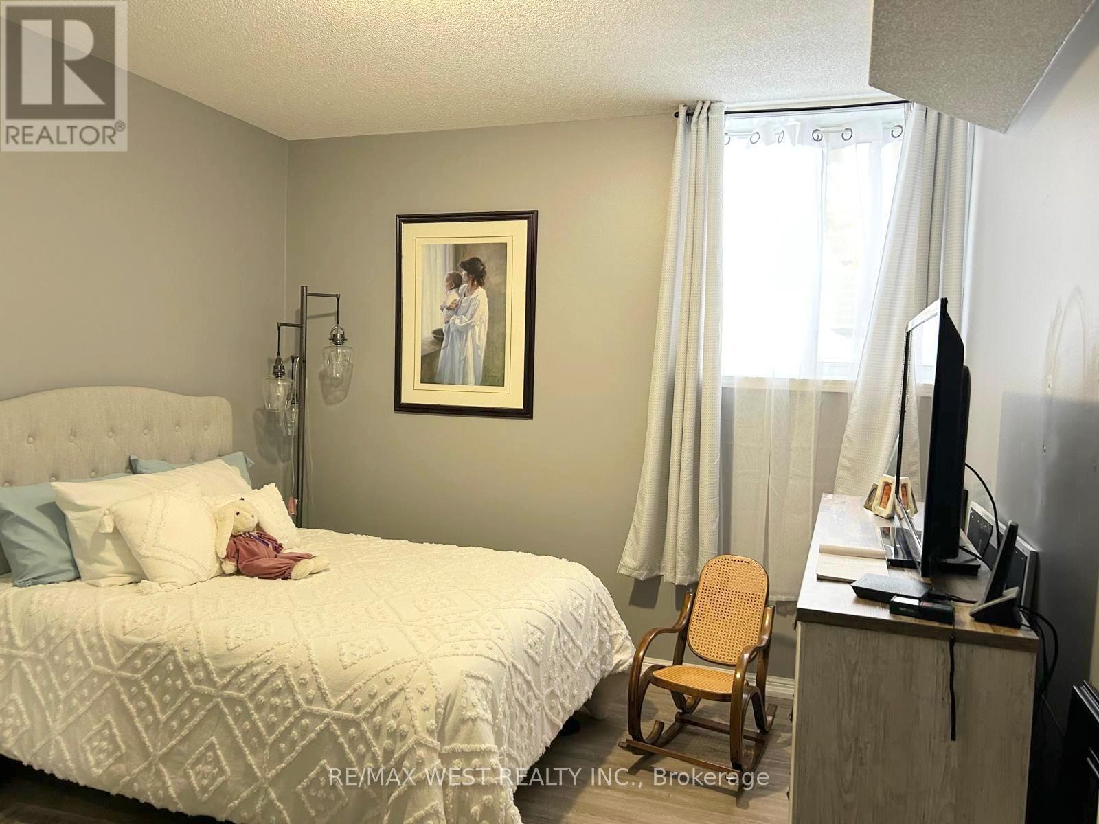 A bedroom with a bed, chair, and a painting on the wall.