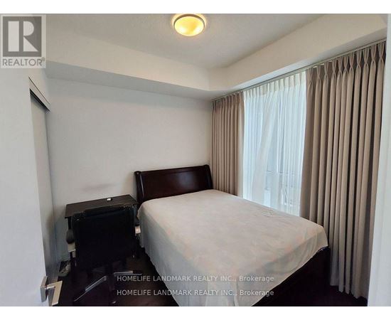 A bedroom with a bed, nightstand, and window with curtains.