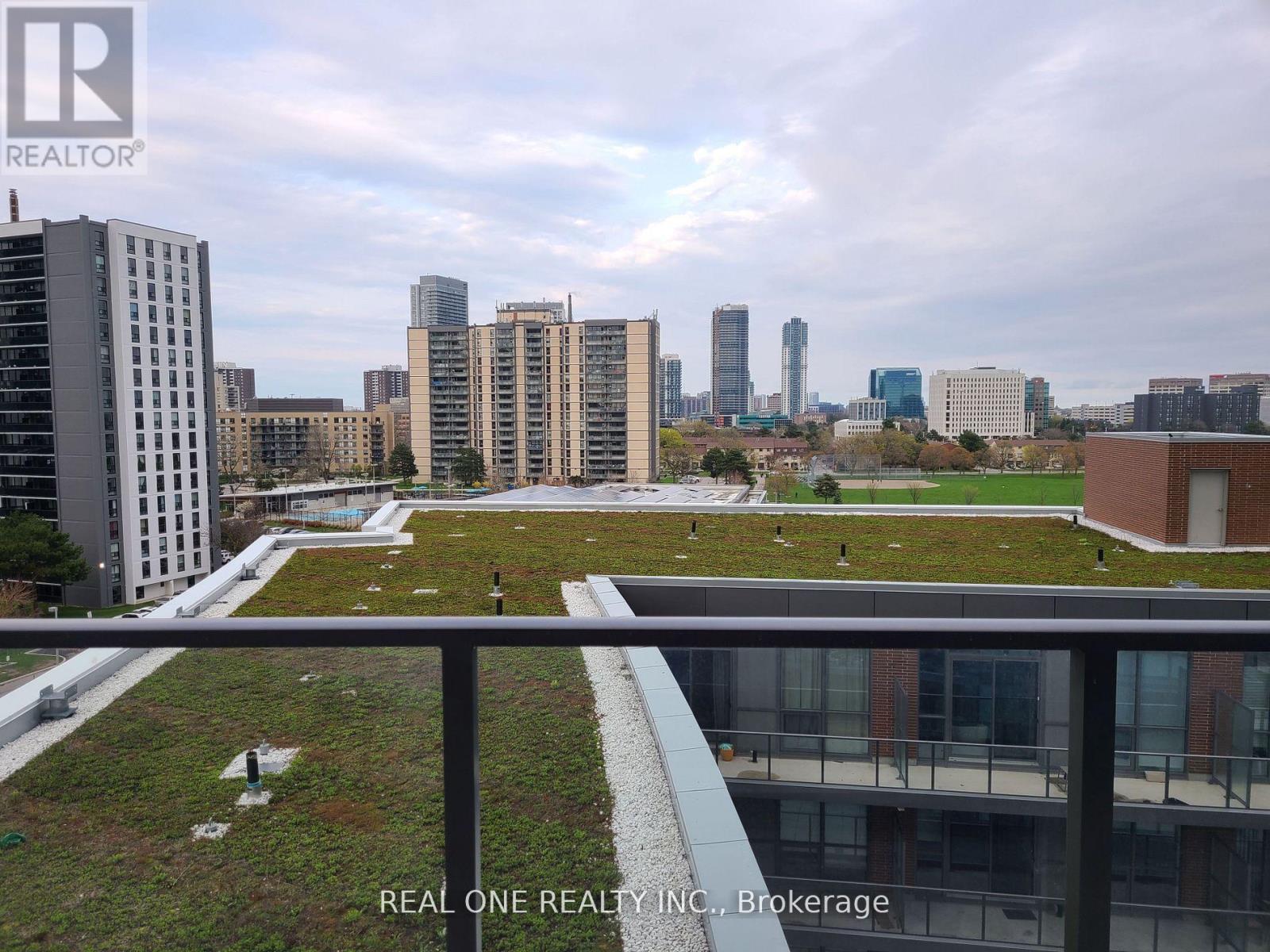 A cityscape with a green space in the foreground and a building with the logo REAL ONE REALTY INC. in the bottom left corner.