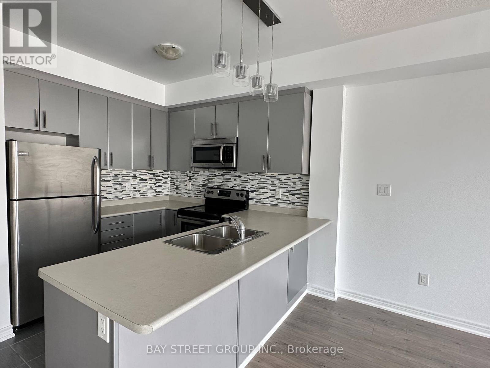 A kitchen with a refrigerator, microwave, and stove top oven.
