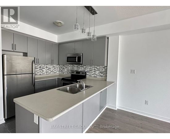 A kitchen with a refrigerator, microwave, and stove top oven.