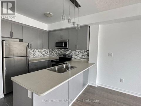 A kitchen with a refrigerator, microwave, and stove top oven.