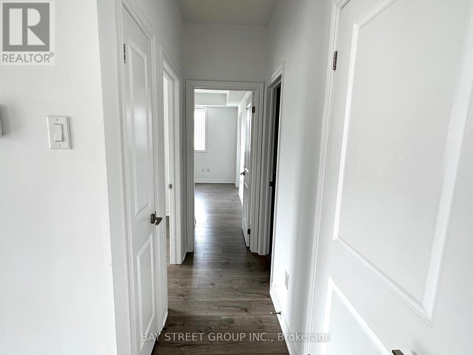 A hallway with white walls and wooden floors.