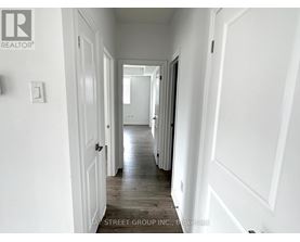 A hallway with white walls and wooden floors.