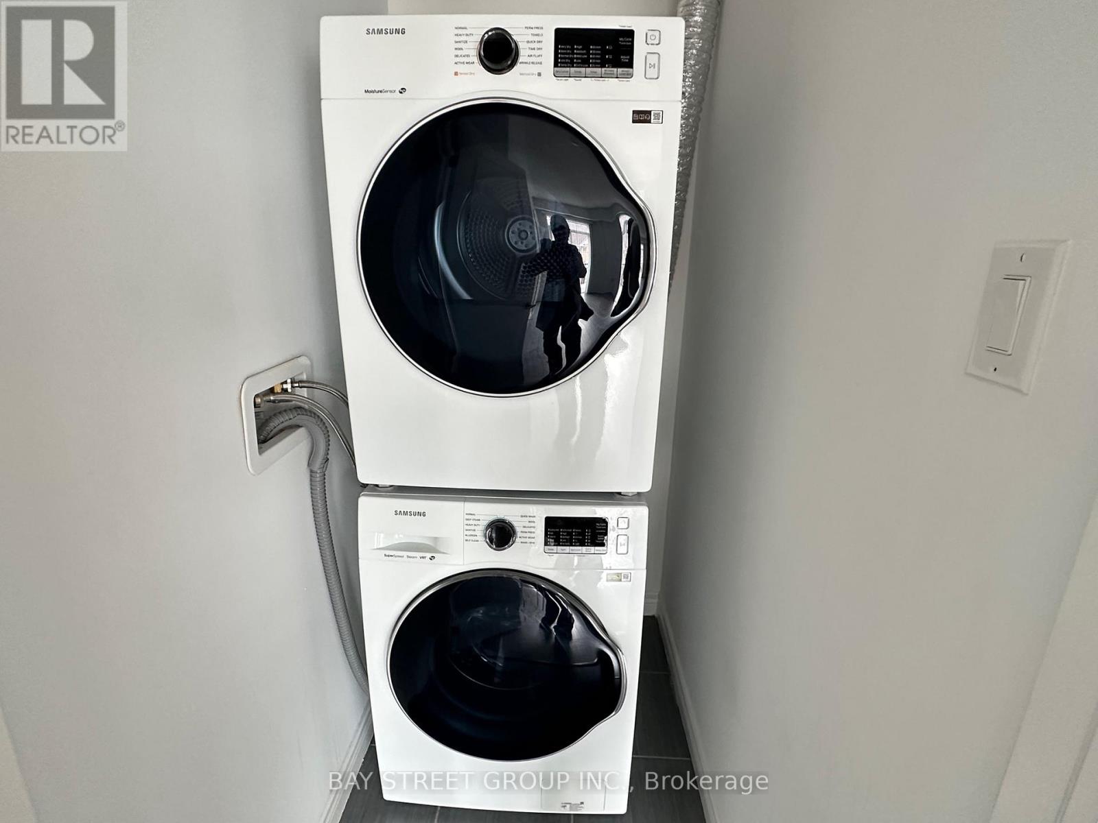 A white Samsung washing machine and dryer in a small room.
