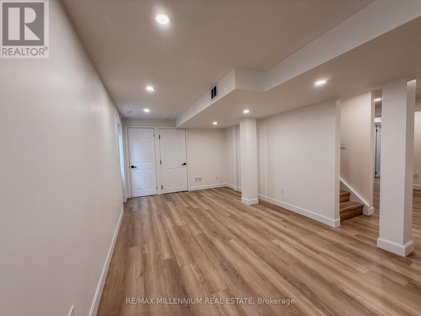A spacious room with wooden flooring and white walls.