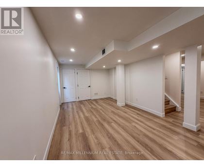 A spacious room with wooden flooring and white walls.