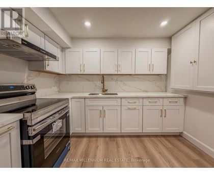 A kitchen with white cabinets and a marble backsplash.