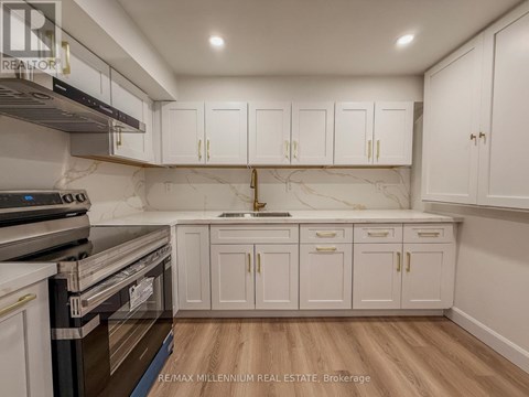 A kitchen with white cabinets and a marble backsplash.