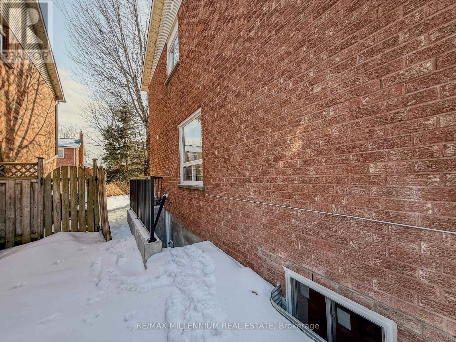 A red brick building with a window and snow on the ground.