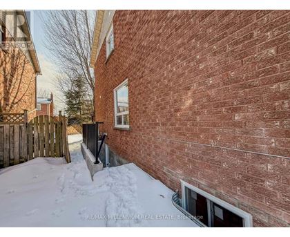 A red brick building with a window and snow on the ground.