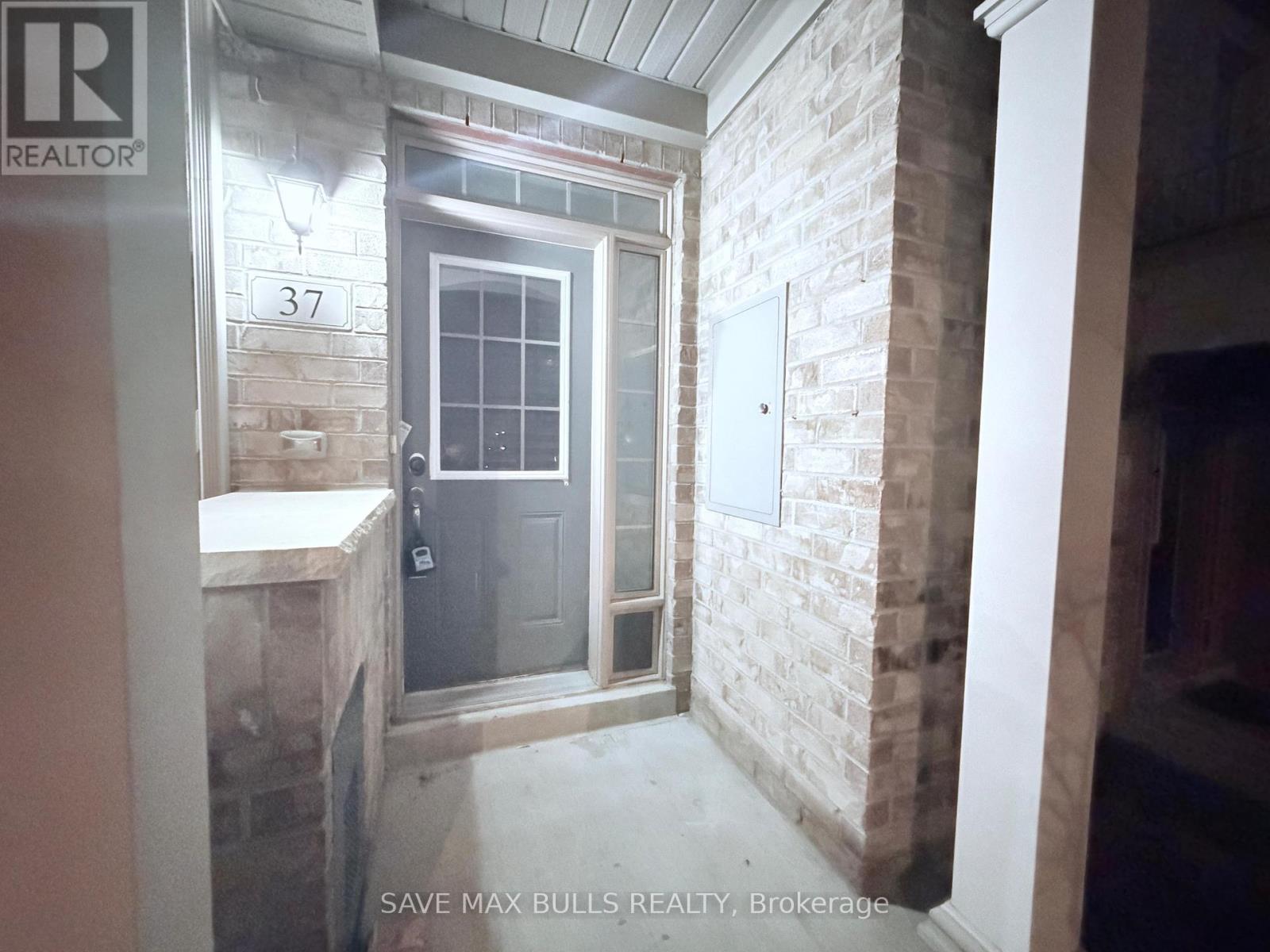 A room with a door and a window with a brick wall.