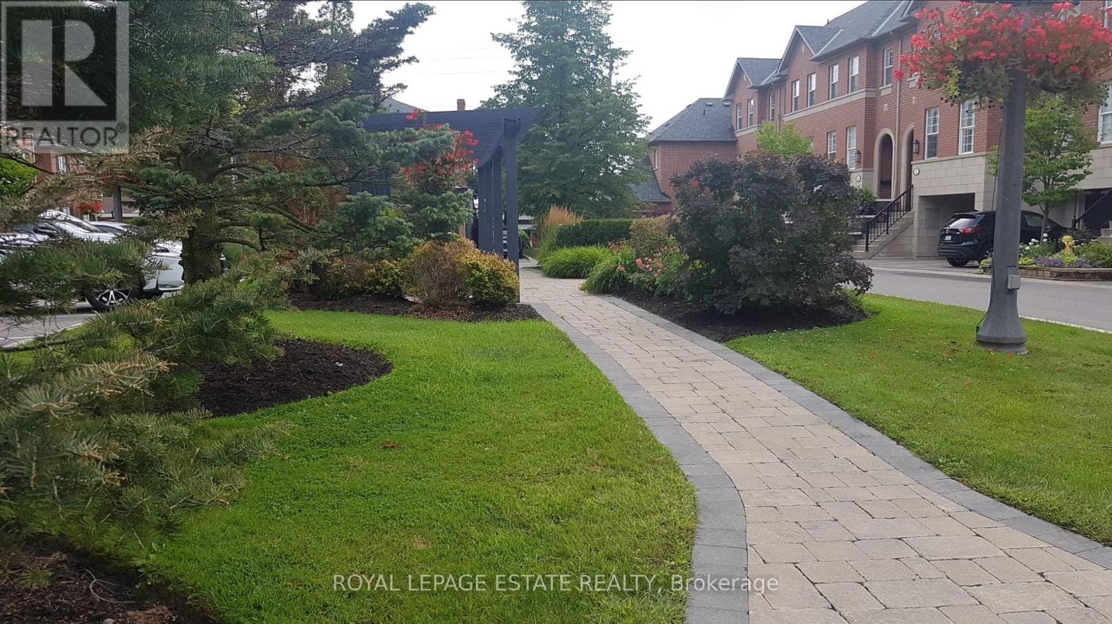 A pathway leads through a landscaped area with a building in the background.